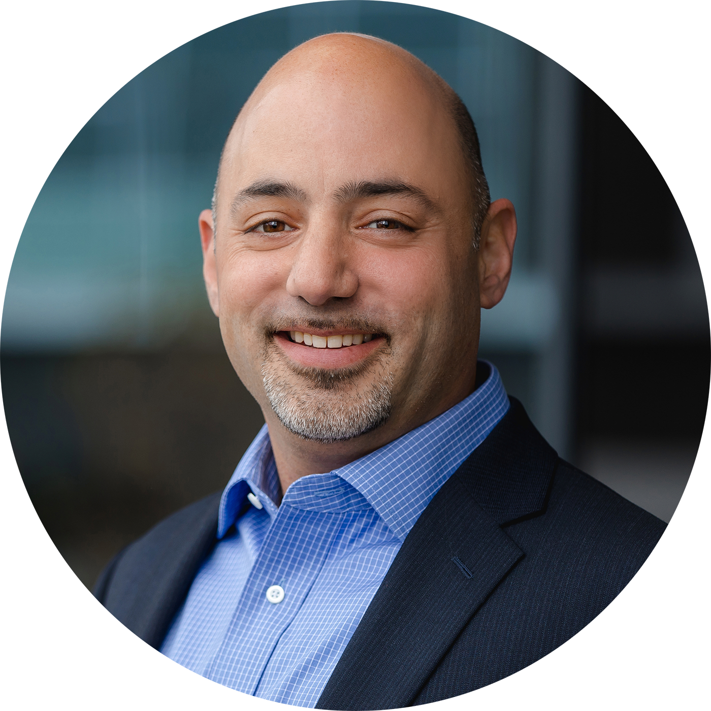 A portrait of Jake Rosenhaft, Co-Founder & CTO of Ceemo.ai. He's a white man smiling at the viewer, with a goatee, wearing a blue button down shirt and navy suit jacket.