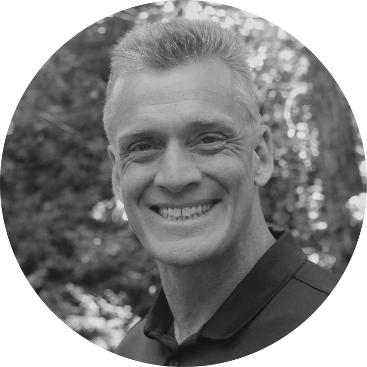 A black & white portrait of Kevin Dick, Managing Partner at Right Side Capital Management. He's a white man smiling broadly at the viewer, with short cut hair, wearing a black polo shirt.