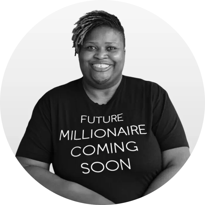 A black & white portrait of Ruby "Sunshine" Taylor, an African American woman smiling at the viewer, wearing a black tshirt with large white text that reads "Future Millionaire Coming Soon." Her hair is short and in tightly coiled braids.